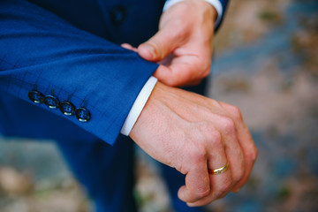 man straightens the cuff of a blue jacket with his hand