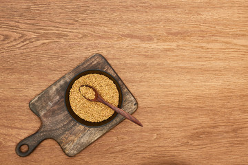 top view of bowls whole grains with spoon on wooden cutting board