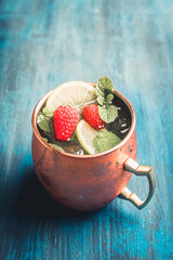 Raspberry and lime cocktail in copper mug (variation of Moscow mule) on the rustic background. Selective focus. Shallow depth of field.