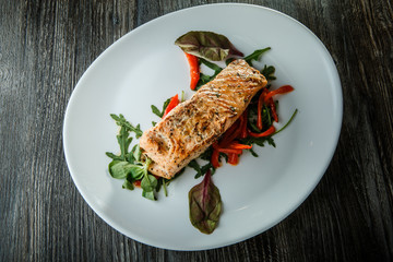top view of baked salmon fillet with green salad and arugula