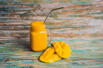 Mango smoothie and steel drinking straw on a painted wooden background