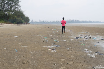 Lok Kawi, Kota Kinabalu, Sabah, Malaysia - September 08, 2019:  Unidentified boy is running on a polluted beach. The beach is full garbage that was washed up from the ocean to the shore. 