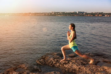 Young woman practicing yoga near river