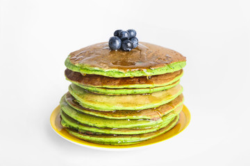 Tasty green pancakes with blueberry on white background