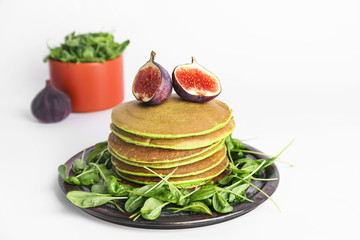 Tasty green pancakes with fig fruit on white background