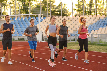 Fototapeta premium Sporty young people running at the stadium