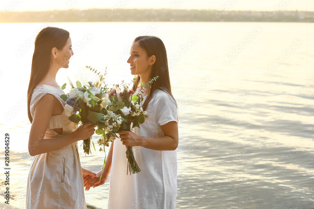 Wall mural Beautiful lesbian couple on their wedding day near river