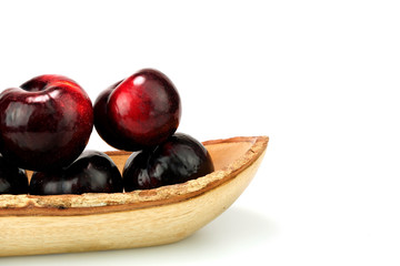Group fresh plum on a wood plate isolated on white background.