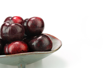 Group fresh plum on a ceramic plate isolated on white background.