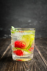 Old fashioned summer cocktail based on gin with raspberry and lime on the rustic background. Selective focus. Shallow depth of field.
