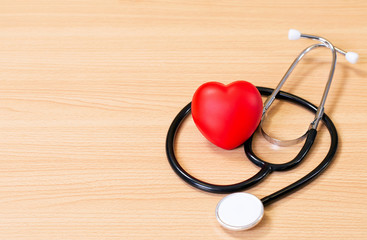 Red heart and stethoscope on wooden table. Doctor tool for heartbeat listening. Healthcare concept. Empty place for text,