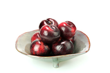 Group fresh plum on a ceramic plate isolated on white background.