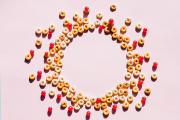 Whole grain cereal rings as circle on soft pink background. Healthy and Delicious breakfast. Top view. Copy space.circle of Breakfast cereal, corn flakes with berries.