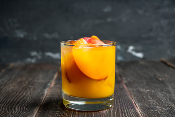 Fresh peach beverage in old fashioned glass on the rustic background. Selective focus.
