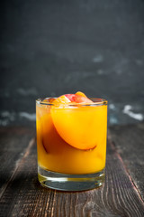 Fresh peach beverage in old fashioned glass on the rustic background. Selective focus.