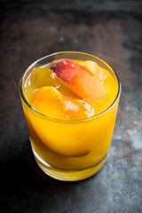 Fresh peach beverage in old fashioned glass on the rustic background. Selective focus.