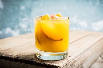 Fresh peach beverage in old fashioned glass on the rustic background. Selective focus.