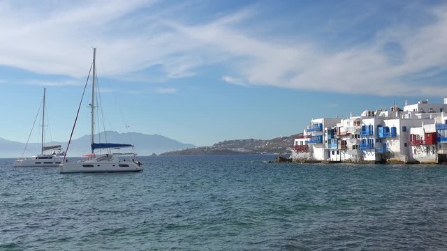 Romantic colorful Little Venice at Mykonos town harbor. Cyclades islands. Sunny day with yachts on Aegean sea and mountains on background. Amazing touristic place, Alefkandra area. Greece vacation