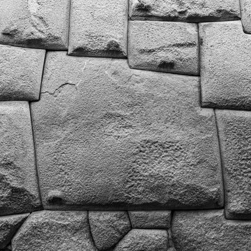 Square black and white photograph of the famous twelve angle stone in the Hatun Rumiyoc street in the historic city center of Cusco, Peru.