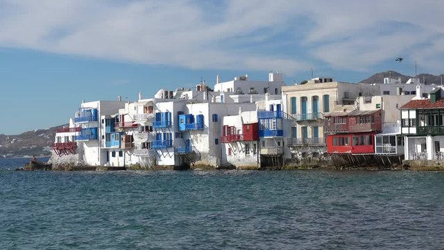 Romantic Little Venice at Mykonos town. Sunny day with yachts on Aegean sea. Alefkandra area. Amazing landscape with colorful buildings, Tourists enjoying restaurants at promenade. Greece vacation