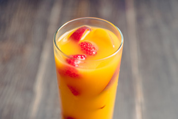 Fresh peach beverage with red ripe raspberry on the rustic background. Selective focus.