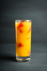 Fresh peach beverage with red ripe raspberry on the rustic background. Selective focus.