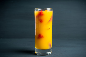Fresh peach beverage with red ripe raspberry on the rustic background. Selective focus.