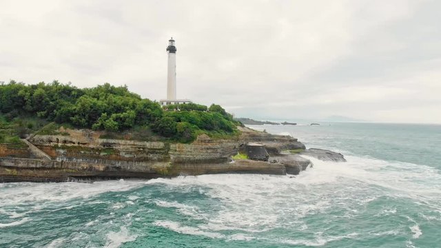 Aerial shot of Biarritz Beach Resort Light House in cloudy day with big Waves crushing on Cliffs - Basque Country South West of France