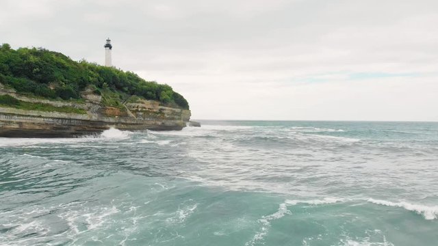 Aerial shot of Biarritz Beach Resort Light House in cloudy day with big Waves crushing on Cliffs - Basque Country South West of France