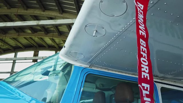 Remove before flight pitot tube cover on small general aviation airplane, protection for air speed measuring instrument, red warning flag on aircraft, closeup