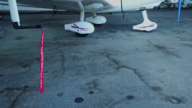Remove before flight pitot tube cover on small general aviation airplane, protection for air speed measuring instrument, red warning flag on aircraft, closeup