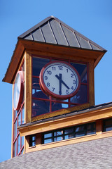 Building top with a clock under bright blue sky on a summer evening