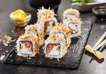 Macro shot of uramaki sushi rolls with cream cheese, salmon, tuna shavings or dried bonito, cucumber, nori. Portion of fresh katsuobushi roll in Japanese restaurant closeup