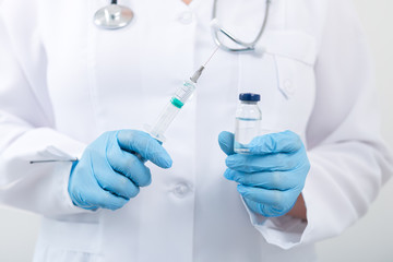 Fototapeta premium Female doctor holding flu vaccine in hands in clinic room