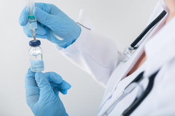 Female doctor holding flu vaccine in hands in clinic room