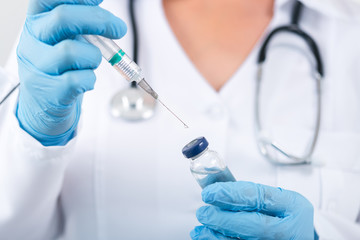 Fototapeta premium Female doctor holding flu vaccine in hands in clinic room