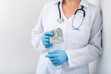 Doctor in clinic with a bundle of dollar bills