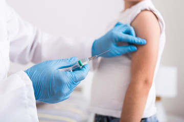 Pediatrician give syringe injecting flu vaccination in arm little boy