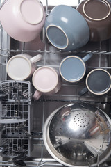 clean metal cutlery and crockery, in the dishwasher, top view