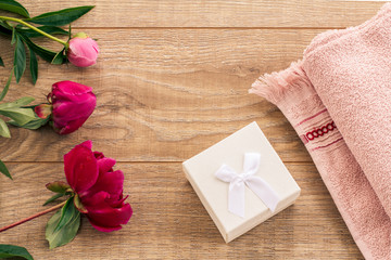 Beautiful bouquet of peonies, gift box and a towel on wooden desk.