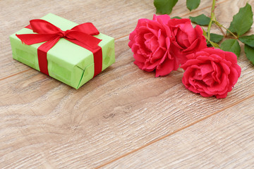 Gift box with rose flowers on the wooden background.