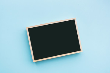 minimal top view image of empty letter to add text on black chalk board over blue paper background. Card and invitation concept. Flat lay, top view, copy space, mockup