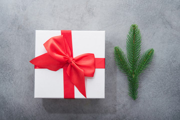 Christmas white box present with red ribbon and fir tree branch