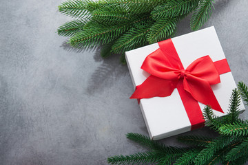 Christmas white box present with red ribbon and fir tree branch