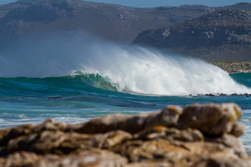 huge crashing wave with mountains in the background