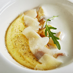 Exquisite Serving White Restaurant Plate of Homemade Italian Cream Polenta with Porcini Mushrooms and Pecorino Cheese Close Up. Fine Italian Dish of Boiled Cornmeal on Natural Black Marble Background