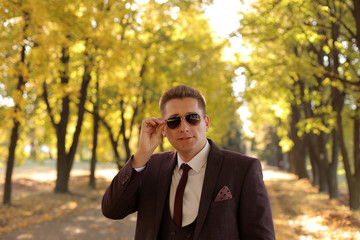 Portrait of a successful happy smiling businessman in sunglasses in an autumn Park in warm Sunny weather.