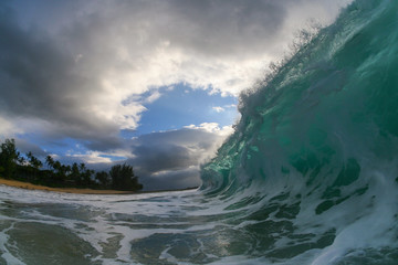huge shore break wave crashing close up at sunset with a moody sky and dramatic clouds