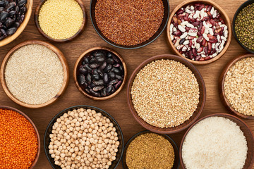 top view of bowls with whole grains and legumes on wooden surface