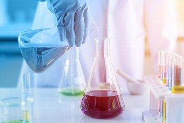 scientist with equipment and science experiments, laboratory glassware containing chemical liquid for research or analyzing a sample into test tube in laboratory